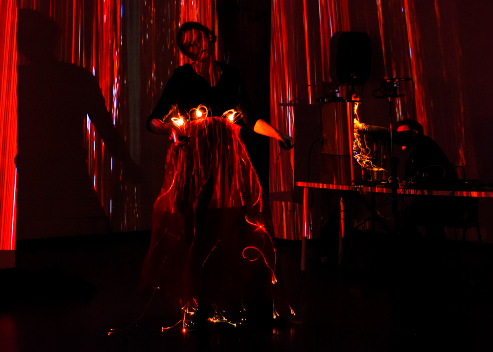 Single channel projection on a woman dancing before red curtains