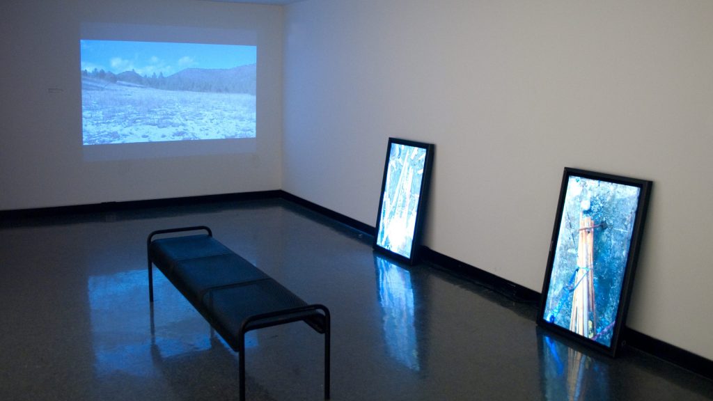 2 monitors leaning against wall showing art, and one projection showing an ocean scene