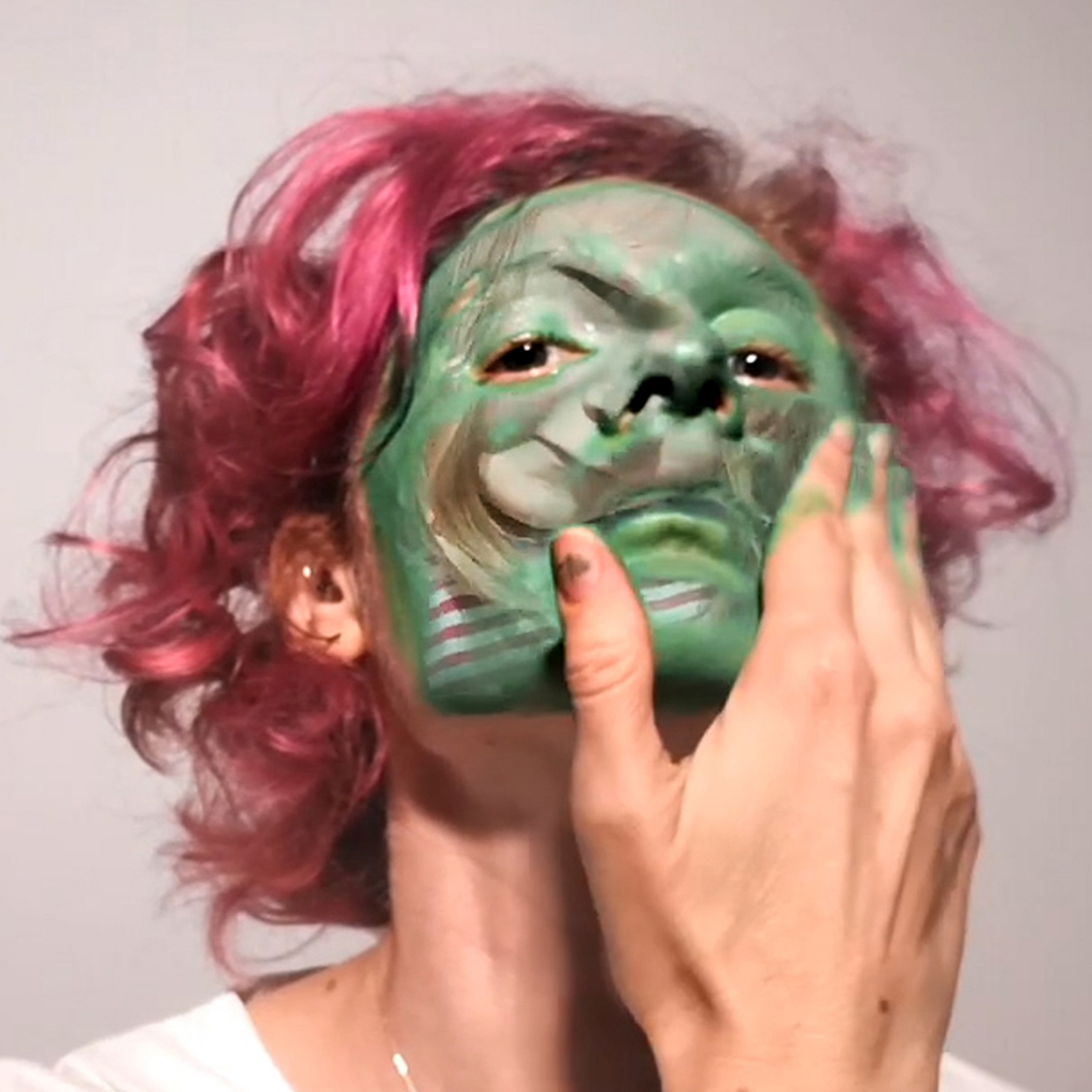 A woman with pink hair and green face paint