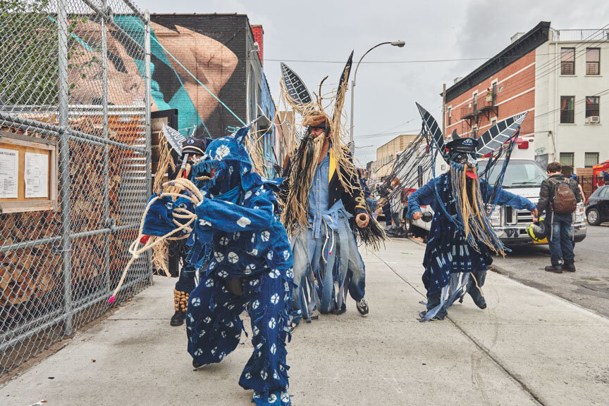 A group of Indigo coloured costume clad people walking along the streets of Brooklyn, New York.