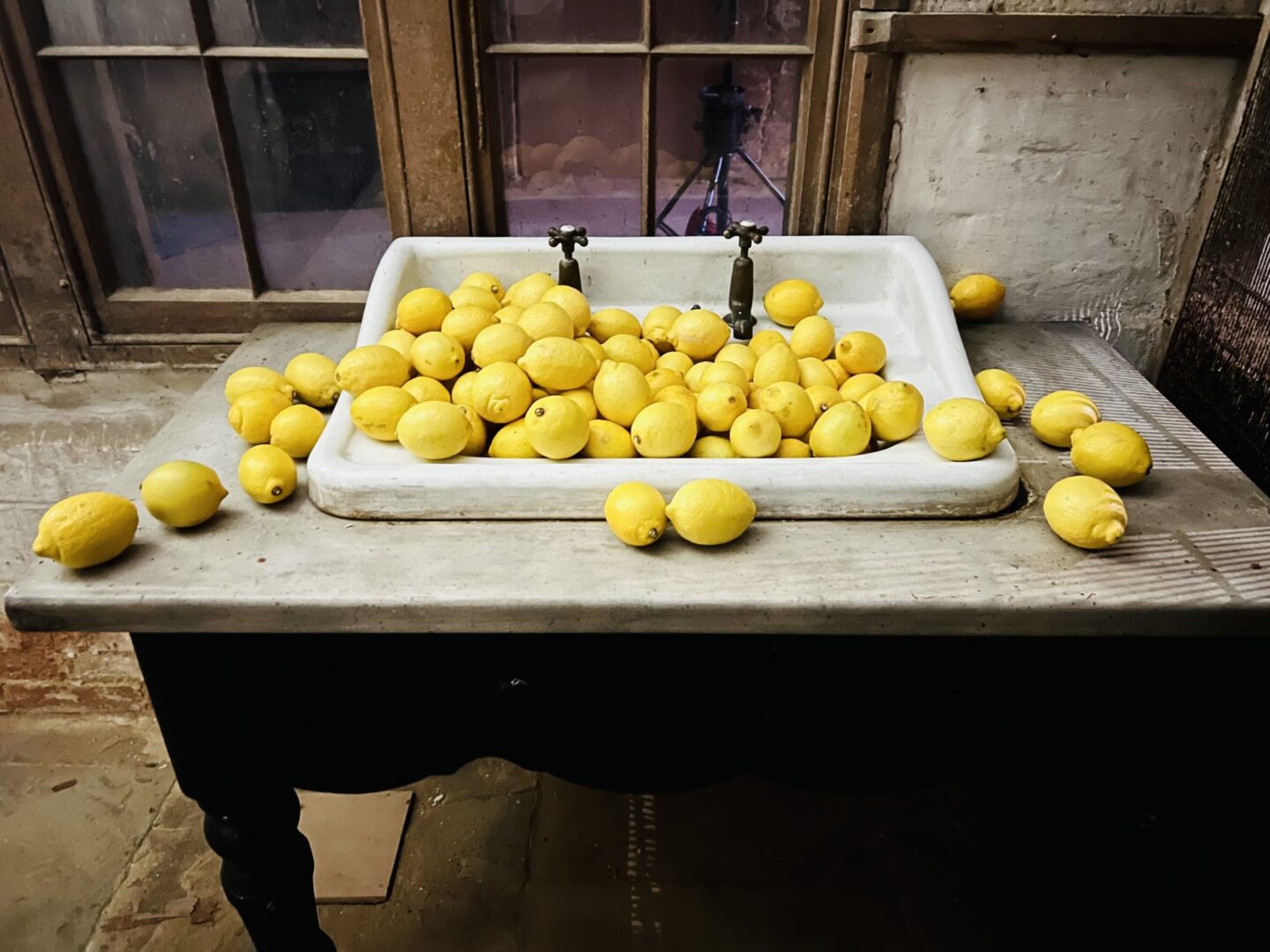 Vintage porcelin sink on wooden table filled with yellow lemons